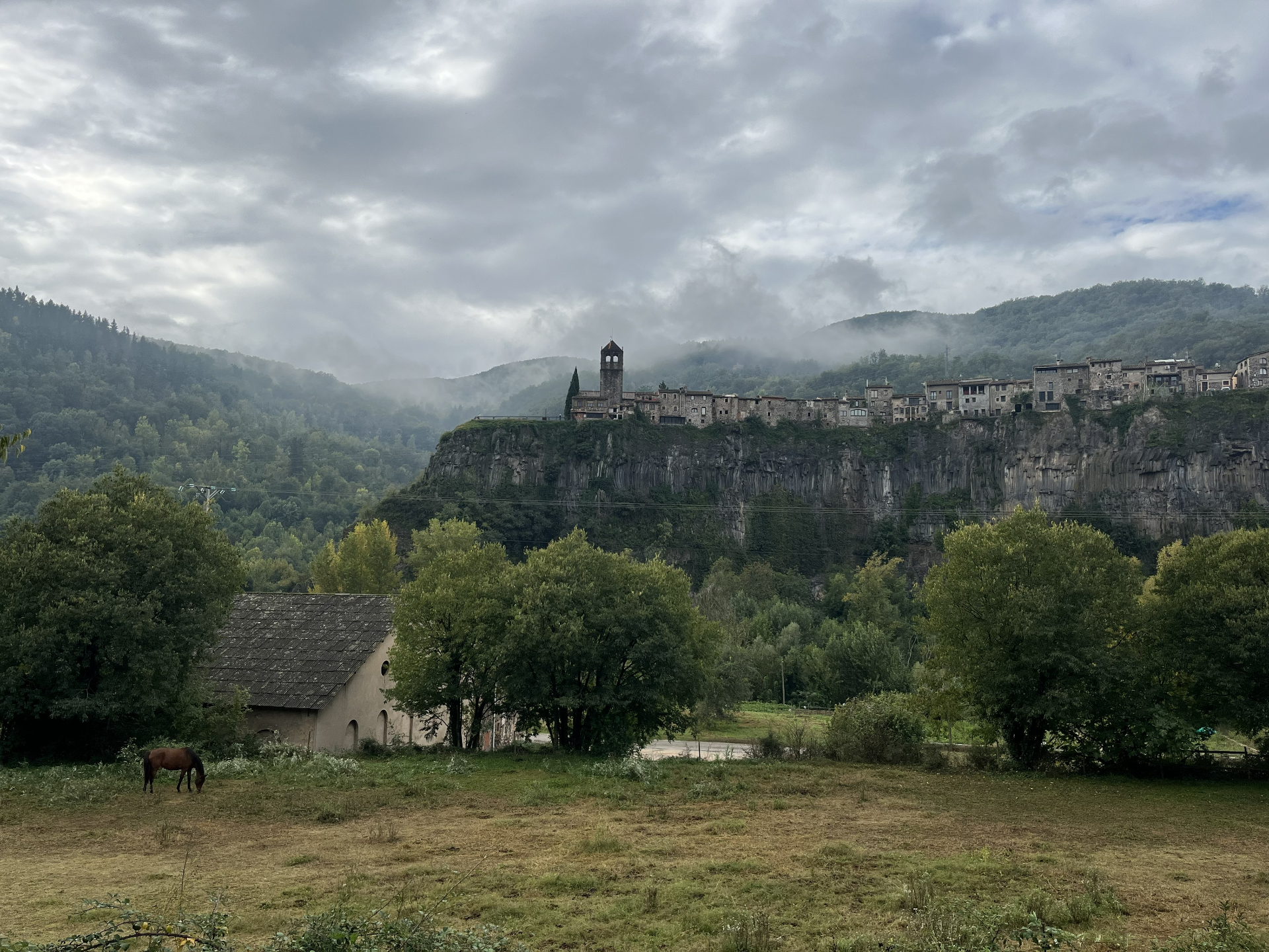Historic Catalan village perched on a basalt cliff above a green valley