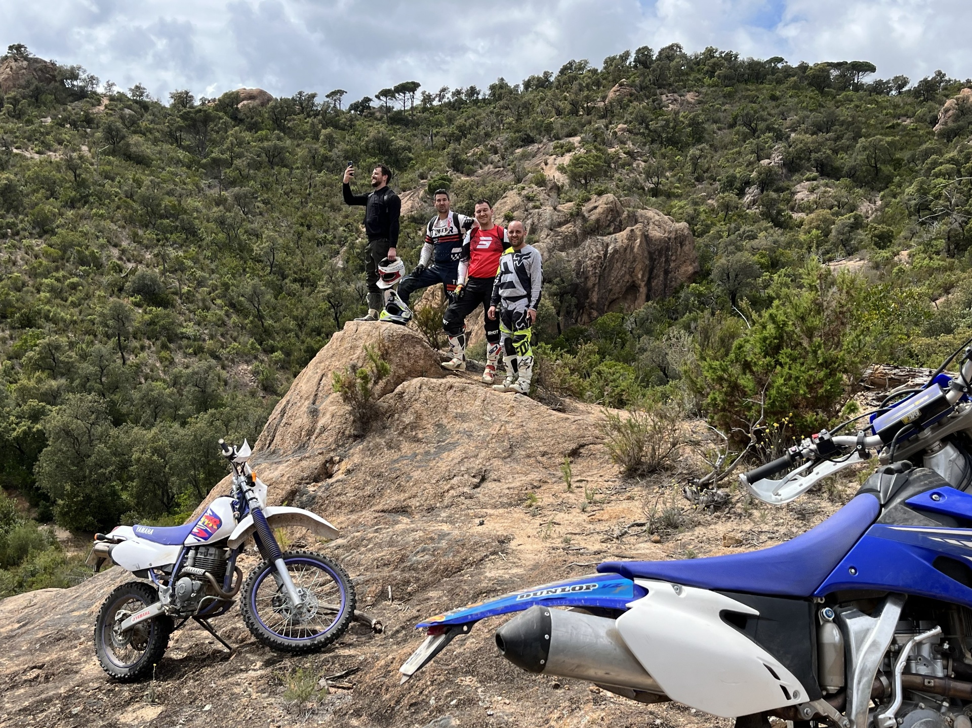 Group of enduro riders taking a break on a rocky Catalonia trail